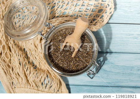 Chia seeds in glass jar. Healthy superfood rich in Omega 3 fatty acids. Dry healthy natural ingredient. Chia grains are falling Chia seeds in glass jar. Healthy superfood rich in Omega 3 fatty acids. Dry healthy natural ingredient. Chia grains are falling 119818921