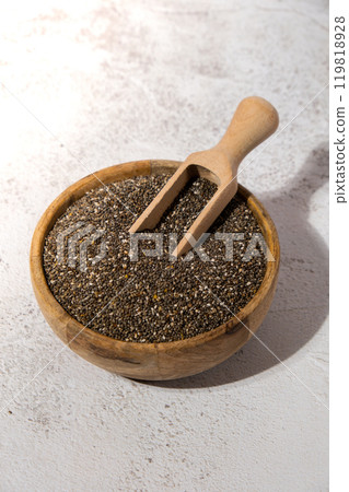 Chia seeds in wooden bowl with wooden spoon. Healthy superfood rich in Omega 3 fatty acids. Dry healthy natural ingredient. Chia grains are falling Chia seeds in wooden bowl with wooden spoon. Healthy superfood rich in Omega 3 fatty acids. Dry healthy natural ingredient. Chia grains are falling 119818928