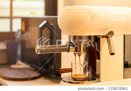 Espresso coffee maker pouring fresh coffee into glass cup on countertop in modern kitchen at home 119818961