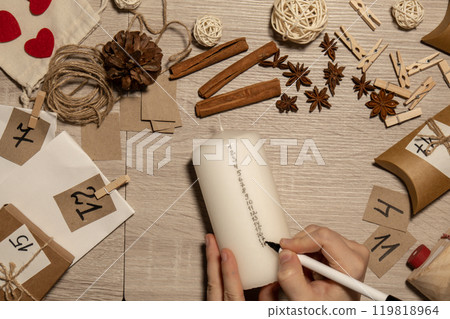 Unrecognizable young woman paint numbers on candles. Female making homemade advent calendar Made with your own hands step by step DIY crafts do it yourself. Preparation to christmas concept. Seasonal Unrecognizable young woman paint numbers on candles. Female making homemade advent calendar Made with your own hands step by step DIY crafts do it yourself. Preparation to christmas concept. Seasonal 119818964