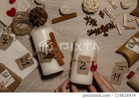Unrecognizable young woman paint numbers on candles. Female making homemade advent calendar Made with your own hands step by step DIY crafts do it yourself. Preparation to christmas concept. Seasonal Unrecognizable young woman paint numbers on candles. Female making homemade advent calendar Made with your own hands step by step DIY crafts do it yourself. Preparation to christmas concept. Seasonal 119818974