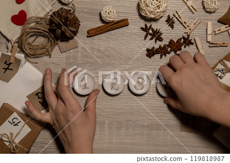 Unrecognizable young woman paint numbers on tea candles. Female making homemade advent calendar Made with your own hands step by step DIY crafts do it yourself. Preparation to christmas concept Unrecognizable young woman paint numbers on tea candles. Female making homemade advent calendar Made with your own hands step by step DIY crafts do it yourself. Preparation to christmas concept 119818987