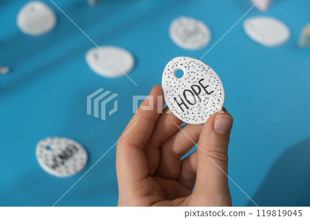 Workshop writing word HOPE on EASTER clay egg Creator is using white air dry clay for making decor to EASTER holiday. Creating hobby recreation activity that involves fingers. DIY crafting 119819045