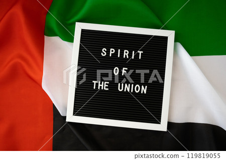 SPIRIT OF THE UNION text frame on United Arab Emirates waving flag made from silk material. Independence Commemoration Day Muslim Public holiday celebration background. The National Flag of UAE SPIRIT OF THE UNION text frame on United Arab Emirates waving flag made from silk material. Independence Commemoration Day Muslim Public holiday celebration background. The National Flag of UAE 119819055