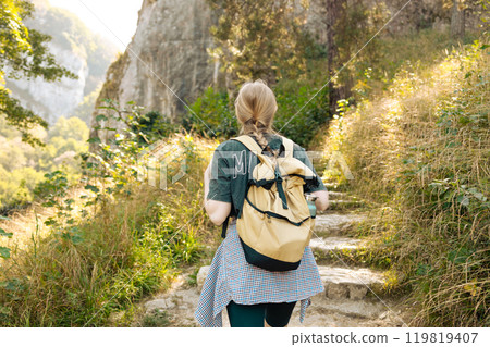Ojcowski park. Portrait of a happy 30s hiker female standing on the slope of mountain ridge against mountains. woman is happy and looking at camera.  119819407