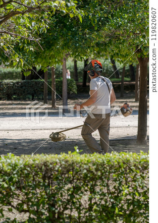 a worker with a hand-held lawn 119820607