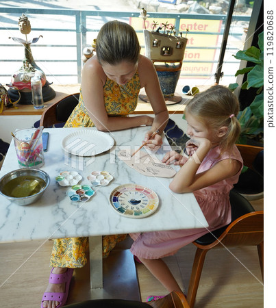 A young mother and her daughter enjoy a creative art session at home  119820688