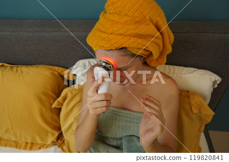 Young woman using infrared massager Young woman using infrared massager 119820841