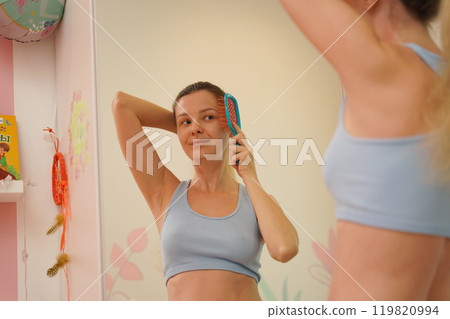 Young woman in a modern bathroom washing her face and brushing her teeth  119820994