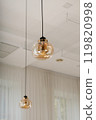 Modern pendant lights with clear glass shades hanging in a minimalist room interior 119820998