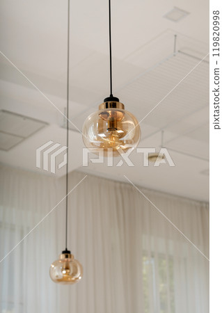 Modern pendant lights with clear glass shades hanging in a minimalist room interior Modern pendant lights with clear glass shades hanging in a minimalist room interior 119820998