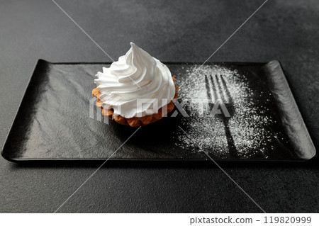 The sand basket is decorated with a high peak of protein cream. A tasty and sweet dessert stands on a black plate on a gray background The sand basket is decorated with a high peak of protein cream. A tasty and sweet dessert stands on a black plate on a gray background 119820999