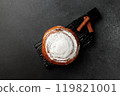 Round, delicious bun with cinnamon and powdered sugar on a black wooden board on a gray background 119821001