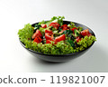 Vegetable salad of tomatoes, cucumbers, onions, lettuce dressed with aromatic dressing in a black plate on a white  background 119821007