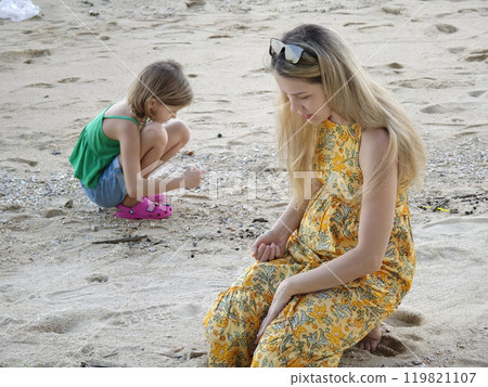 A mother and her daughter as they collect shells together A mother and her daughter as they collect shells together 119821107