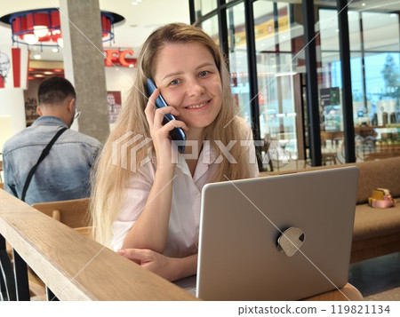 A young woman enjoys coffee while working on her laptop  119821134