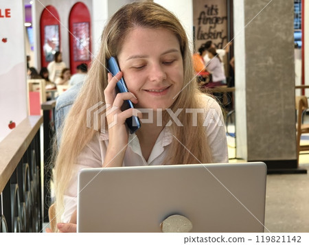 A young woman enjoys coffee while working on her laptop A young woman enjoys coffee while working on her laptop 119821142