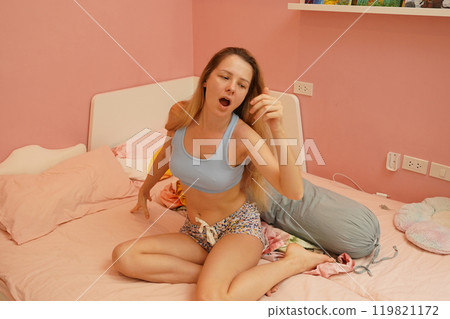 A young woman is enjoying a wonderfully serene morning in her bedroomnd A young woman is enjoying a wonderfully serene morning in her bedroomnd 119821172