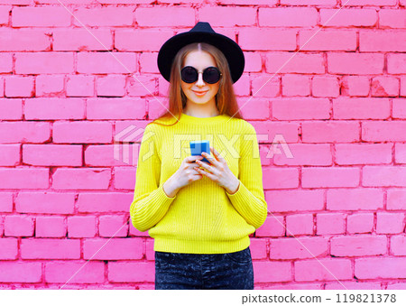 Stylish modern young woman with smartphone, teenage girl holding phone on colorful pink background 119821378