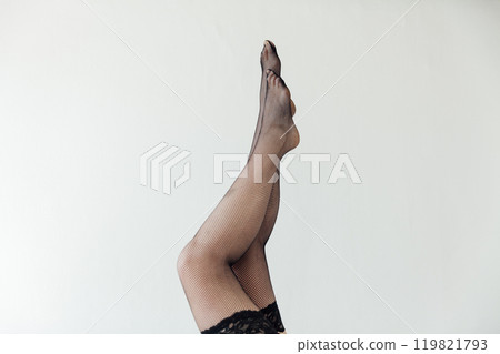 Beautiful female legs in black tights stockings on a gray background Beautiful female legs in black tights stockings on a gray background 119821793