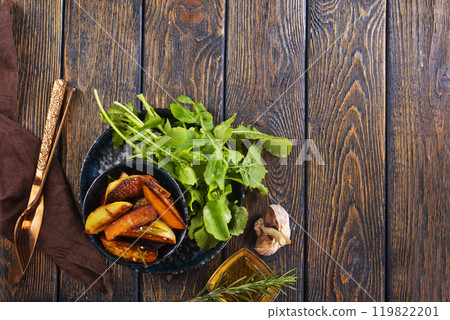 Baked potato wedges with addition sea salt and rucola on wooden background 119822201