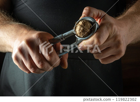 A chef peels a walnut with a nutcracker. A low-key concept for cooking with walnuts 119822302