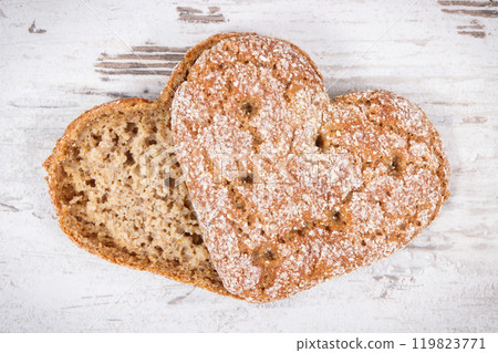 Fresh wholegrain bread in shape of heart for breakfast. Old rustic background 119823771