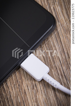 Black smartphone and connected white cable of charger. Telephone charging 119823775