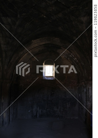 Dark stone room with a small window casting light on the interior. Dark stone room with a small window casting light on the interior. 119823858