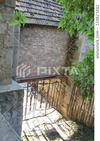 Old stone and brick walls in a narrow outdoor alley with greenery. Old stone and brick walls in a narrow outdoor alley with greenery. 119823882