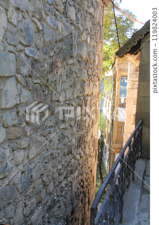 Narrow alley between old stone buildings with metal railing. Narrow alley between old stone buildings with metal railing. 119824003