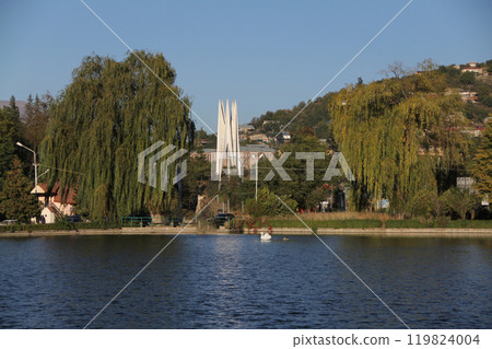 Lakeside view with willow trees and distant white monument on a hill. Lakeside view with willow trees and distant white monument on a hill. 119824004