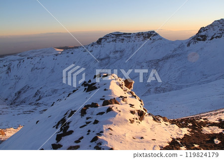 Stunning Snowy Mountain Landscape with Clear Blue Sky and Prominent Peak in the Distance 119824179