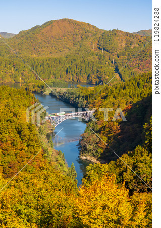 穿越只見川大橋和秋葉覆蓋的山脈的機車 穿越只見川大橋和秋葉覆蓋的山脈的機車 119824288
