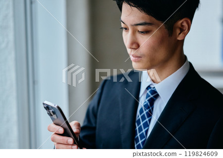 一名20多歲的年輕人正在操作智慧型手機 119824609