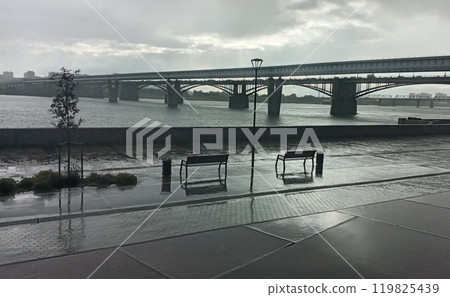 Cityscape view with a long bridge over a wide river under a cloudy sky in the distance 119825439