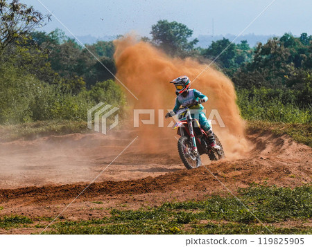 A biker creates a large cloud of dust and debris, Motocross concept A biker creates a large cloud of dust and debris, Motocross concept 119825905