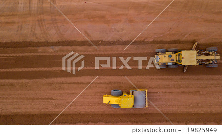 Aerial view road motor grader flatting dirt road surface, Motor grader road construction grader industrial machine on construction site of new road, Mortor grader on work. 119825949