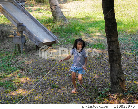 Children play outdoors on a wooden playground in a park. Happy girl playing on slide in playground in summer. Children play outdoors on a wooden playground in a park. Happy girl playing on slide in playground in summer. 119825979
