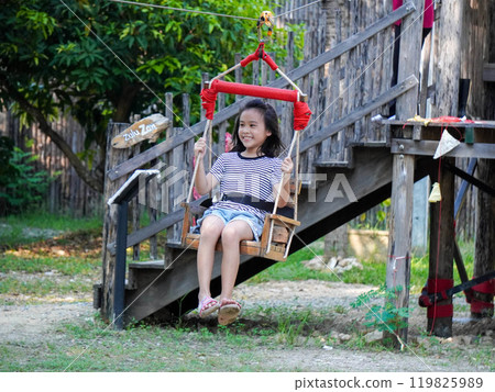 Kids play outdoors on a playground with modern slides, rope net bridges, climbing swings, climbers in summer. Kids play outdoors on a playground with modern slides, rope net bridges, climbing swings, climbers in summer. 119825989