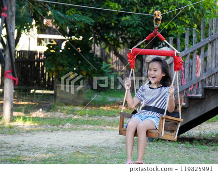 Kids play outdoors on a playground with modern slides, rope net bridges, climbing swings, climbers in summer. Kids play outdoors on a playground with modern slides, rope net bridges, climbing swings, climbers in summer. 119825991