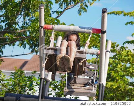 Kids play outdoors on a playground with modern slides, rope net bridges, climbing swings, climbers in summer. Kids play outdoors on a playground with modern slides, rope net bridges, climbing swings, climbers in summer. 119825993