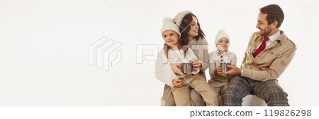 Joyful family sharing hot drinks after ice-skating session. Parents and children dressed in cozy winter clothes. Warmth and happiness on cold day. 119826298