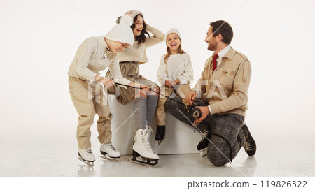 Father kneeling down to help his young daughter lace up her ice skates. Cozy caring moment showcases family love and winter traditions Father kneeling down to help his young daughter lace up her ice skates. Cozy caring moment showcases family love and winter traditions 119826322
