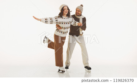 Happy young couple, man and woman dressed in cozy warm clothes, ice skating with fun and joy isolated on white background Happy young couple, man and woman dressed in cozy warm clothes, ice skating with fun and joy isolated on white background 119826370