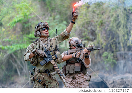 Close up two militaries or soldiers stay in battlefield near the river with one hold flare fireworks and one stand with point gun forward direction during outdoor practice. 119827137