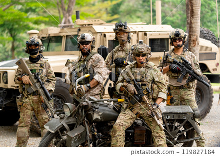 Group of militaries or soldiers stay in front of humvee car and one sit on motorcycle also look at camera during outdoor practice. 119827184