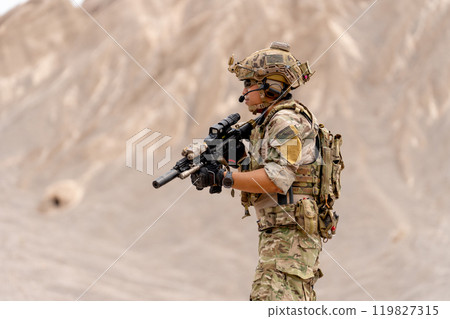Military or soldier with holding gun and look to left side and stay in battlefield near the mountain during outdoor practice. Military or soldier with holding gun and look to left side and stay in battlefield near the mountain during outdoor practice. 119827315