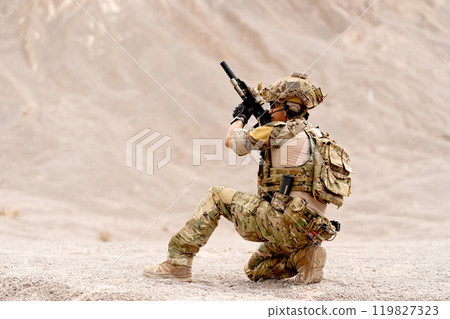 Military or soldier with hold gun and point up also sit in battlefield near the mountain during outdoor practice. Military or soldier with hold gun and point up also sit in battlefield near the mountain during outdoor practice. 119827323