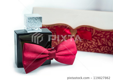 Elegant Black Perfume Bottle With Red Bow Tie and Decorative Box on White Background. Elegant Black Perfume Bottle With Red Bow Tie and Decorative Box on White Background. 119827862